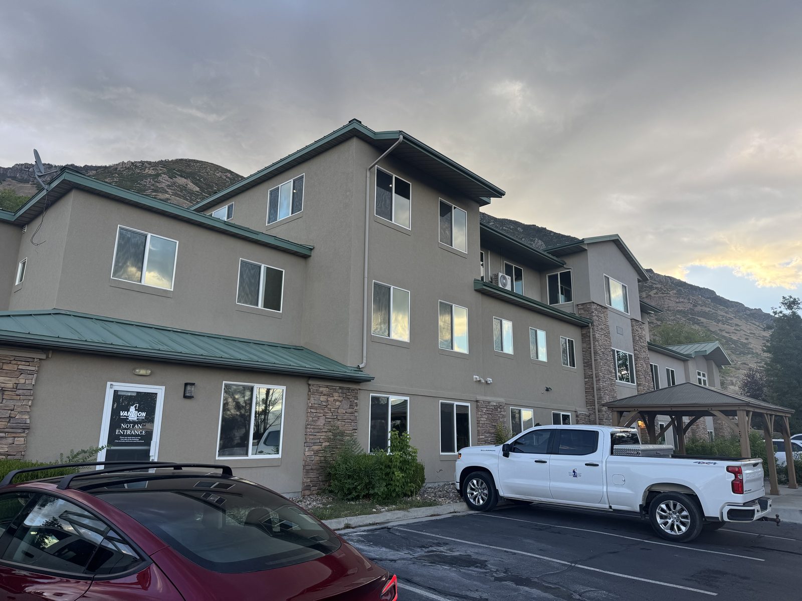 Three-story multi-unit building on the Wasatch Front with mountains behind it, every window fitted with a fresh screen.